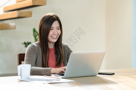 桌子工作场所亚洲商业妇女使用技术笔记本电脑和移动话在家工作室内现代住宅自由职业者和企家创者和和企主社会距离和自我责任中从事家庭工图片