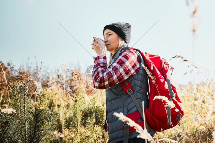 女子在暑假旅行中休息和用咖啡喝一杯妇女站立在路边看望远方背着负包徒步穿越高草地的女子在山上过着与自然相亲的暑假闲暇快乐积极图片