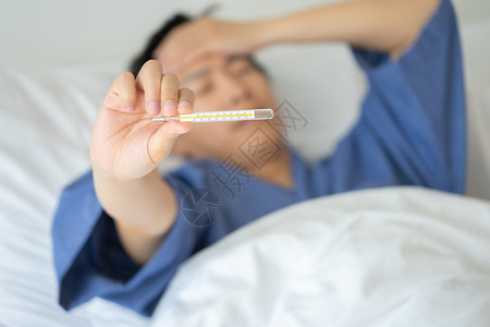 不良亚洲英俊的年轻男子亚洲人Hypothermia被用发烧来测量床上躺着让自己在家为病人提供医疗护理的概念在床上安眠白种人长椅图片