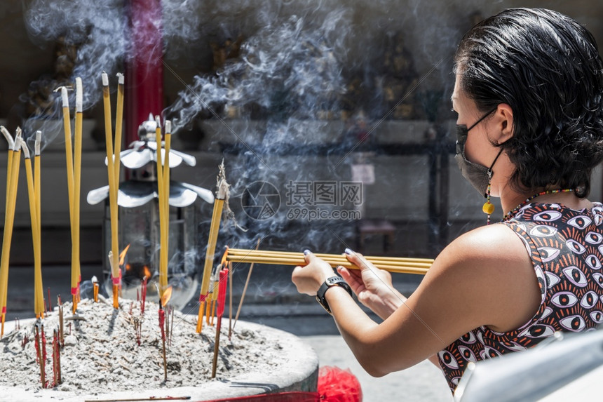 她自己戴着医用口罩以防感染的亚洲妇女正在寺庙里烧香口罩以保护自己免受冠状的侵害在城市被看到选择焦点见过图片