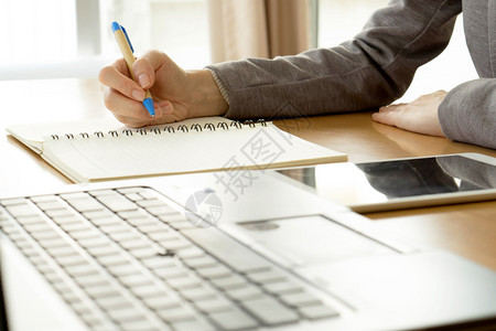 女桌子在办公室用笔记本电脑写纸和打字的封闭工作妇女技能图片