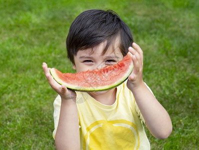 在夏天的户外吃新鲜西瓜的男孩图片