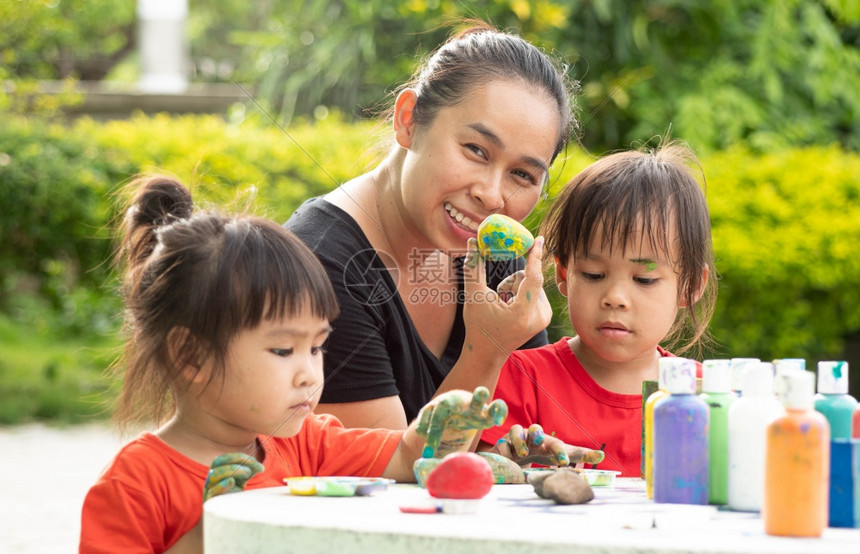 结石经过家庭亚洲两个小妹与母亲在炎热的夏日享受用石块和木砖上涂满丙烯漆手画的亚洲两姐妹她们与母亲一起过着温暖的夏日Conterr图片