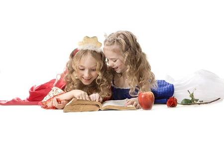 俄语人们两个美丽的小姑娘穿着公主服装的金发长头穿着公主服装在白色背景上读一本魔法书红色和蓝帝国礼服红和蓝色帝国礼服种族教育高清图片素材