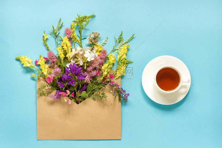 快乐春天手工艺品袋和一杯草药茶中花地多彩的生锈古花朵蓝绿树背景的香草茶早上好夏天茶时间晚会请用平板套餐卡女士图片