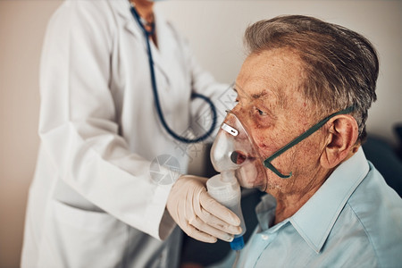 女士室内的医生在吸入期间对患有肺病Covid19或冠状治疗的老年男子施用药物在检疫期间到家探诊的博士生人数病的图片