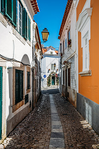 入口葡萄牙卡斯伊老城粉刷房屋和墙壁之间的狭窄鹅卵石小巷街道葡萄牙卡斯伊老城粉刷房屋和墙壁之间的狭窄鹅卵石小巷街道老的正面图片