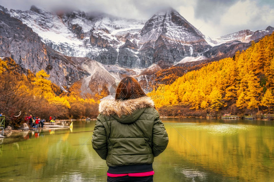 季节树叶背包客在珍珠湖上寻找和观光景象秋季雪山在森林自然保护区旅行与游著名的地点和标概念中下着雪山的珠湖上游览图片
