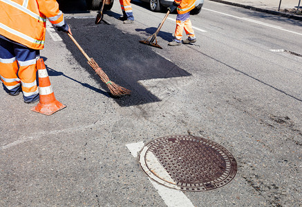 行业修井附近道路工人作组在修复路段时用各种手工具铁铲马转扫把修理公路时工作组将热沥青倒在甚至用铲子一个水平和扫帚打的地块上工作组图片