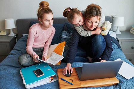 移动的技术在CCOVID19检疫期间在家庭笔记本电脑网上课程学习络研讨会课程时正在远学习做工作业的母和女儿坐在床上的妇女计算图片