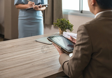 男人棕色西装企业经理使用PC平板电脑坐在办公桌和秘书处穿着蓝色礼服作笔记站在老板面前工作概念商业公司常设图片
