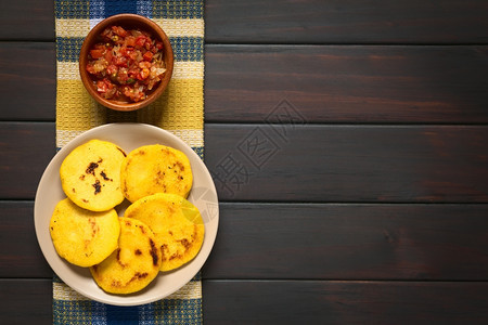 自制哥伦比亚红番茄和洋葱煮在阿雷帕碗里由黄或白玉米饭制成传统上在哥伦比亚和委内瑞拉用天然光照着黑木头食用哥伦比亚阿雷帕与霍加奥苏图片