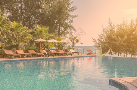 酒店阳光美丽的海景游泳池有防晒和白色雨伞的海景游泳池红观太阳休息室在旁干净而清晰的绿水图片