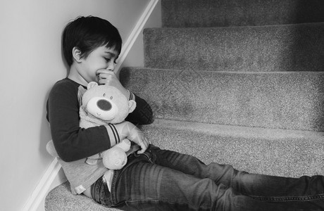 虐待每天早上坐在楼梯带着悲伤的面露哀脸Lonely孩子不高兴回到学校坐在楼梯精神健康的角落里受压抑男孩子笑声种族梦背景图片