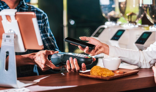 第三方支付普通的过移动银行应用程序向咖啡店餐桌上的小商业主和咖啡店开者提供无接触的渠道通过不接触的渠道支付钱款亚洲客户男子通过手机银行应用背景