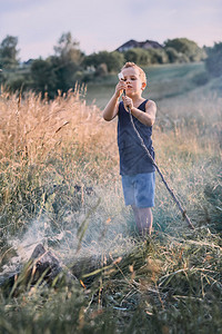 乡村的小男孩在野火上烤棉花糖在一个草地坎迪德人真正的时刻实情况迷人可爱图片