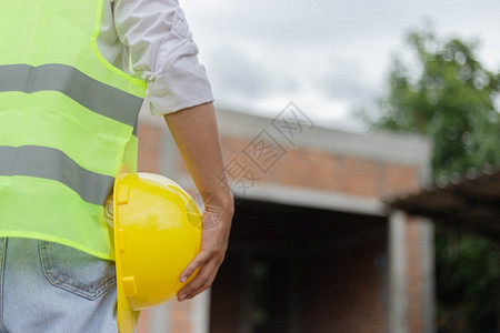 装修男建筑工人身着白色顶上面盖有亮石灰背心黑色手表和浅蓝牛仔裤站立并戴着芥子气安全帽职员恢复图片