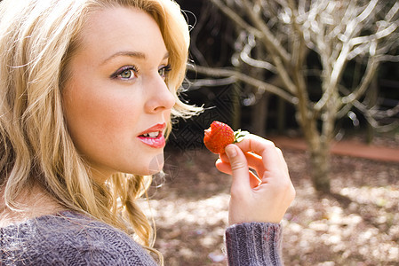 吃草莓的年轻女人女性青年微笑金发女郎晴天青少年乐趣水果头发树叶图片