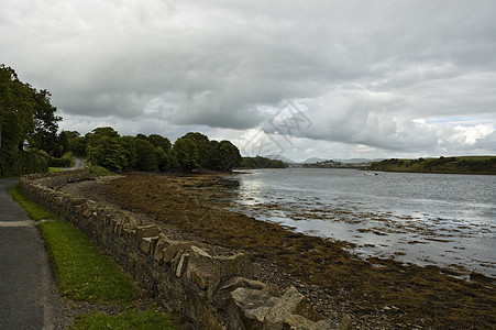 Donegal湾石头藻类爬坡丘陵海岸栅栏支撑海滩天空海洋图片