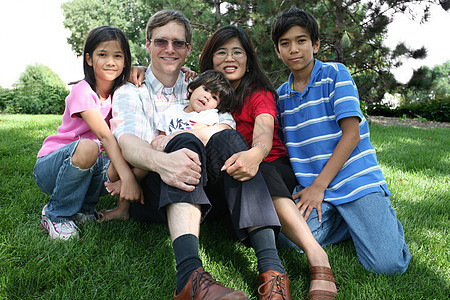 大型多种族家庭坐在草坪上树木混血朋友们母亲兄弟姐妹院子混血儿婴儿微笑儿童图片