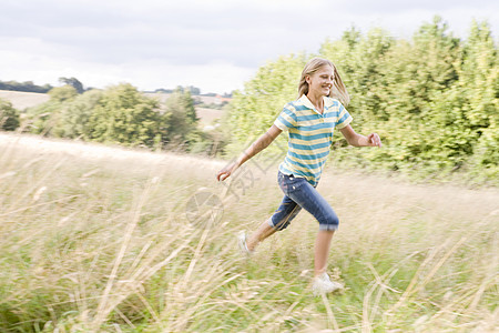 年轻女孩在田里微笑地奔跑图片