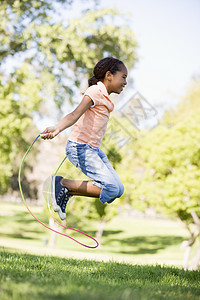 年轻女孩在户外笑着跳过绳子跳跃微笑跳绳享受乐趣健康女性孩子农村图片