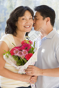 丈夫和妻子带着鲜花亲吻和微笑接吻相机情感男性花束场合夫妻女士女性礼物图片