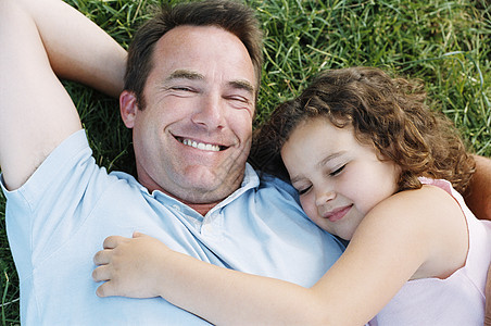 父亲和睡着的女儿在户外微笑图片