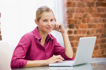 坐在办公室 带着笔记本电脑微笑的女商务人士中年人士桌子商务成人女士技术职场水平生意人图片