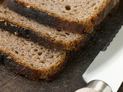 购物委员会上的Rye Bread的切片砧板熟食锯齿状谷物水平食物厨艺刀具晚餐杂粮图片