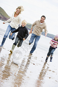 家庭在海滩上笑着玩足球图片