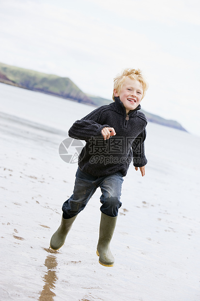 在海滩上微笑的年轻男孩海洋小男孩孩子们男性孩子相机衣服活力海岸跑步图片