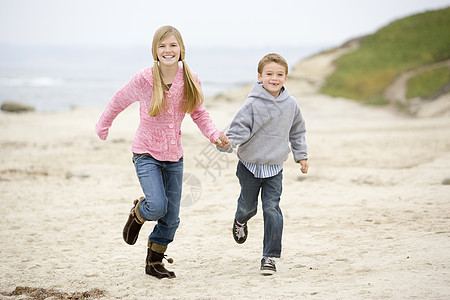 两个小孩在海滩上微笑着手笑着跑的幼童女性衣服男生海洋姐姐两个人女孩儿子海岸男性图片