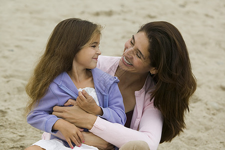 母亲和女儿在海滩上女儿们影响妈妈们拥抱孩子们海岸妈妈孩子中年牙裔图片