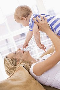 母亲在起居室抱着婴儿微笑女士玩具女儿女孩笑声妈妈女性拥抱家庭家长图片