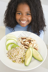 厨房的年轻女孩在吃大米水果和坚果时微笑图片