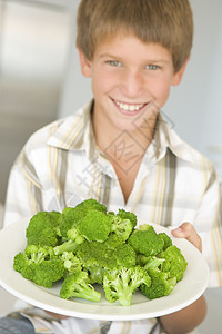 厨房里的小男孩在吃花椰菜 笑着孩子们孩子蔬菜健康饮食青菜儿童食品一个男孩生产零食图片