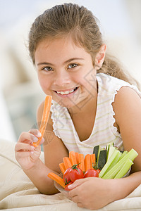 年轻女孩在客厅里吃一碗蔬菜 微笑着笑芹菜生产饮食小吃根茎类食物萝卜享受儿童食品图片