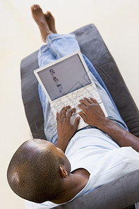 使用笔记本电脑坐在椅子上的人高架客厅休息室座位互联网男性躺椅成人技术上网图片