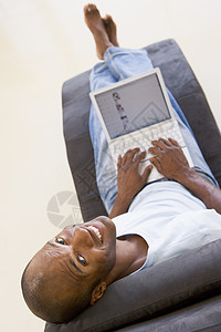 手持笔记本电脑微笑坐在椅子上的人图片