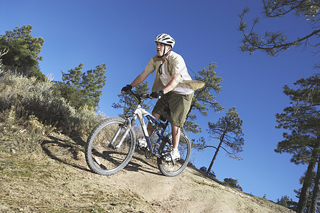 年轻人在山上骑着自行车离开公路图片