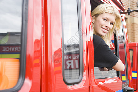 女消防员坐在一辆消防车的出租车上消防窗户服务倾斜司机消防队员水平红色女士情况图片