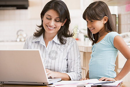 厨房里有手提笔记本电脑和文件的女子和少女家庭研究拉丁商业家长互联网技术女士女儿女孩图片