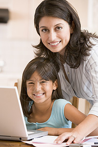 厨房里有手提笔记本电脑和文件的女子和少女女儿女孩两个人家庭桌子拉丁微笑女士商业女性图片