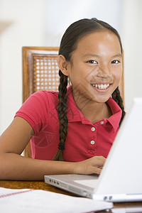 餐厅里带着笔记本电脑的年轻女孩微笑着孩子们监督桌子冲浪家庭作业休息室女性客厅互联网技术图片