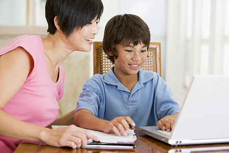 帮助年轻男孩使用笔记本电脑的女子在餐厅做家庭作业 S冲浪桌子家长客厅互联网男生小男孩妈妈男性研究图片