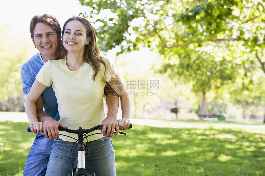 在户外骑自行车的情侣微笑着女子踪迹农村享受男性相机公园两个人山地女士图片