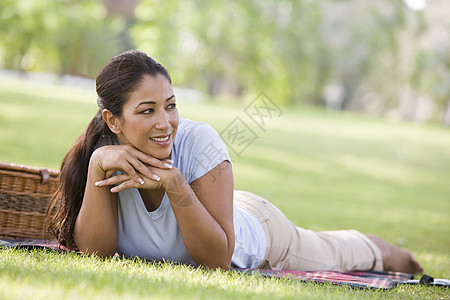露着野餐篮子微笑躺在公园户外的妇女焦距成年人种族情感幸福餐垫闲暇情绪水平毯子图片