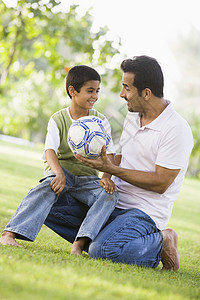 父亲和儿子在户外公园里拥抱和微笑爸爸们孩子情感男士身份家长家庭孩子们小学生中年图片