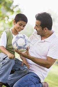 父亲和儿子在户外公园里拥抱和微笑爸爸身份男士孩子们情绪幸福中年爸爸们家庭家长图片